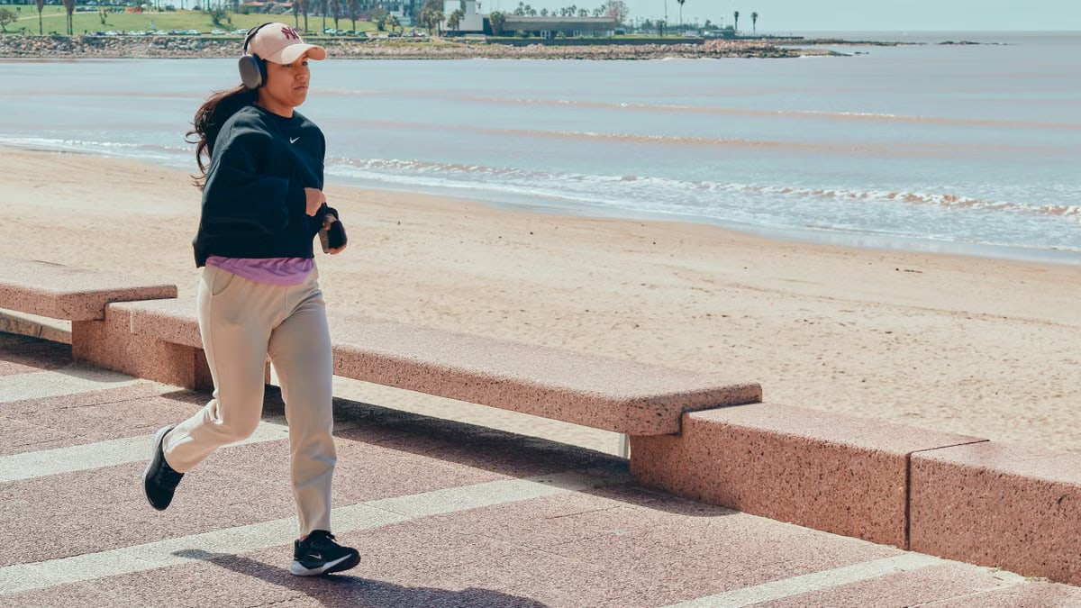 A woman jogs along the beachfront pathway in Montevideo, Uruguay, enjoying a sunny day.